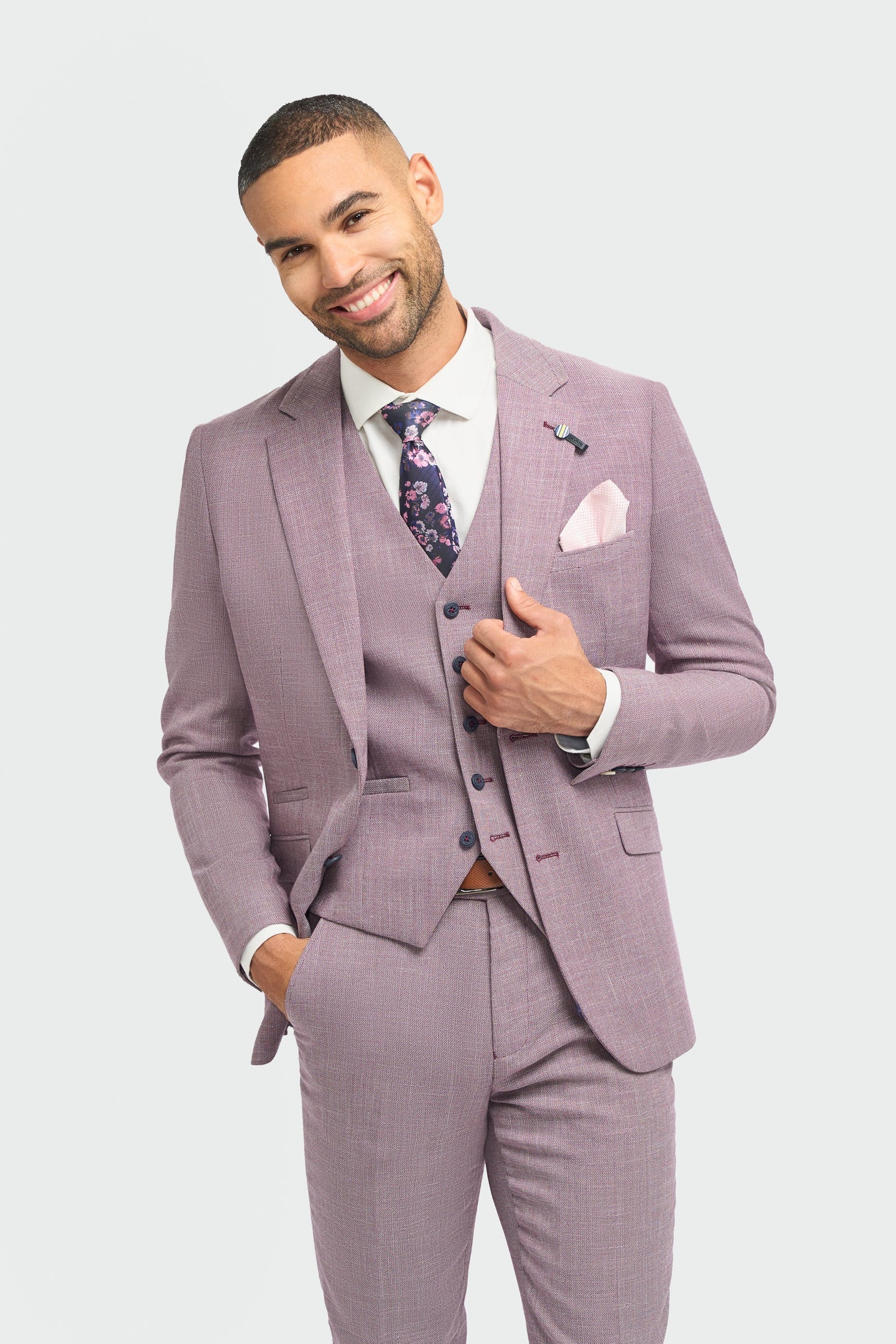 Man wearing a light purple suit with a white shirt and patterned tie on a light gray background