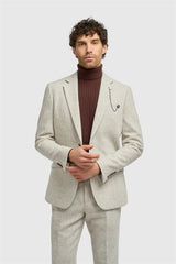 Man wearing a light gray suit with a brown turtleneck sweater on a white background