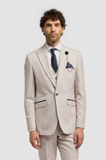 Man wearing a beige suit with a white shirt and brown shoes on a light gray background